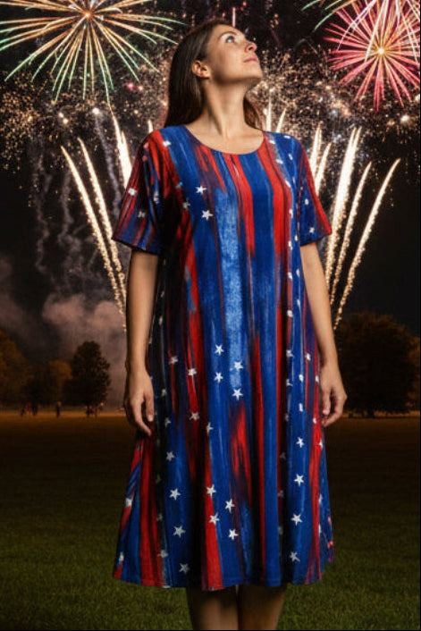 Woman in a red, white, and blue dress standing in front of a vibrant fireworks display.
