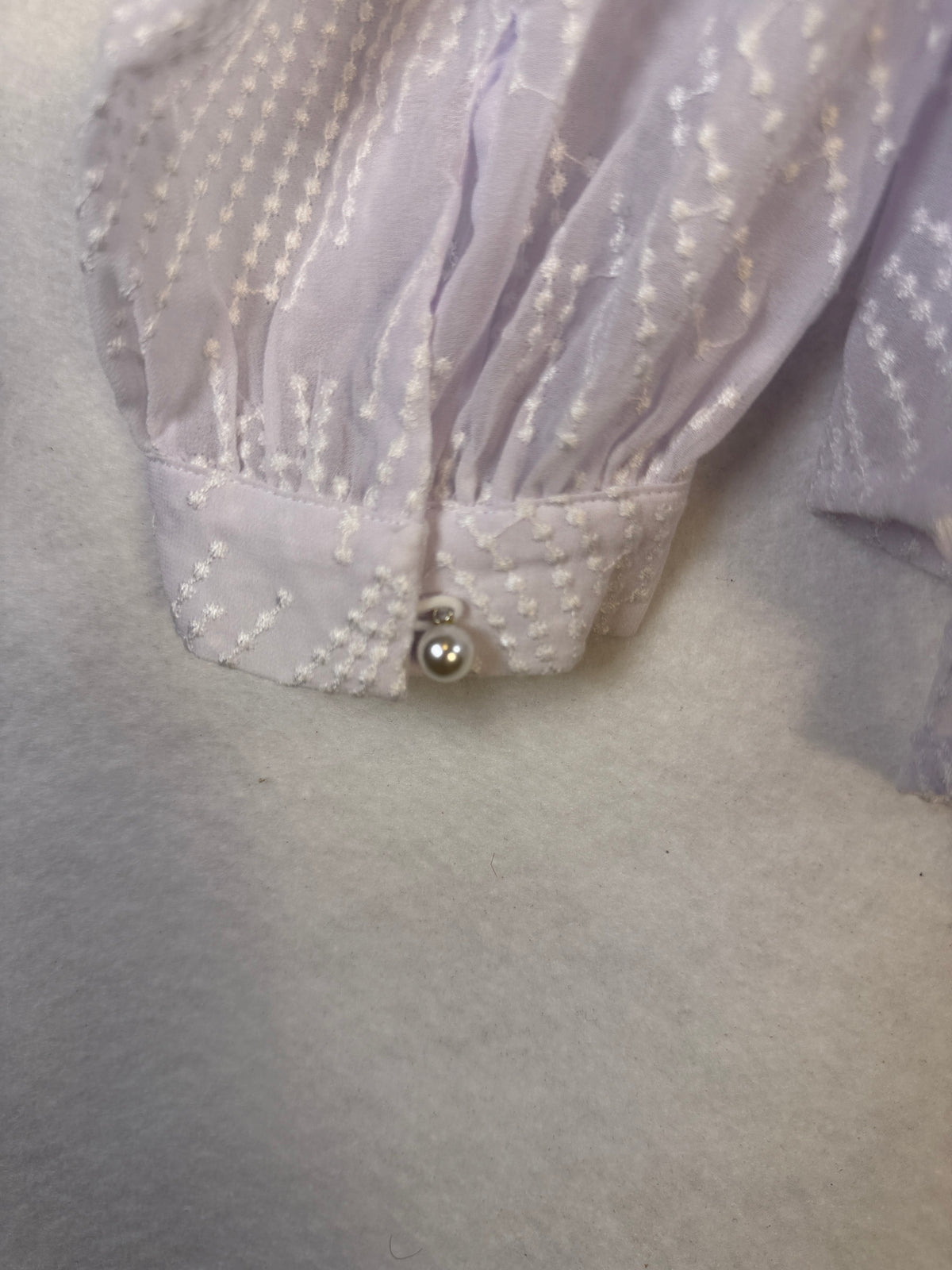 Back of white Oleada blouse showing gathered yoke and curved hem